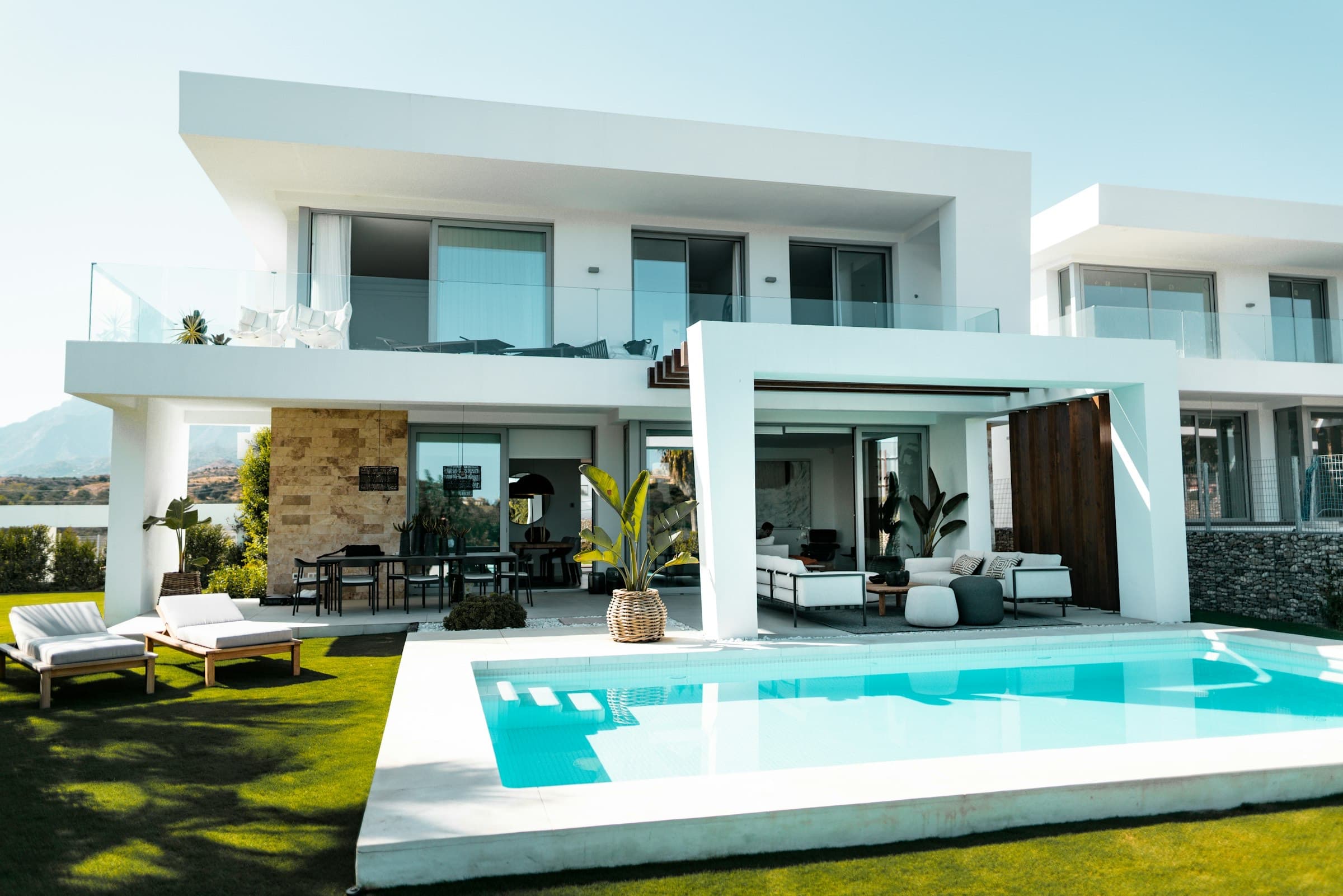 White two-storey villa with a rectangular pool, lawn and covered terrace
